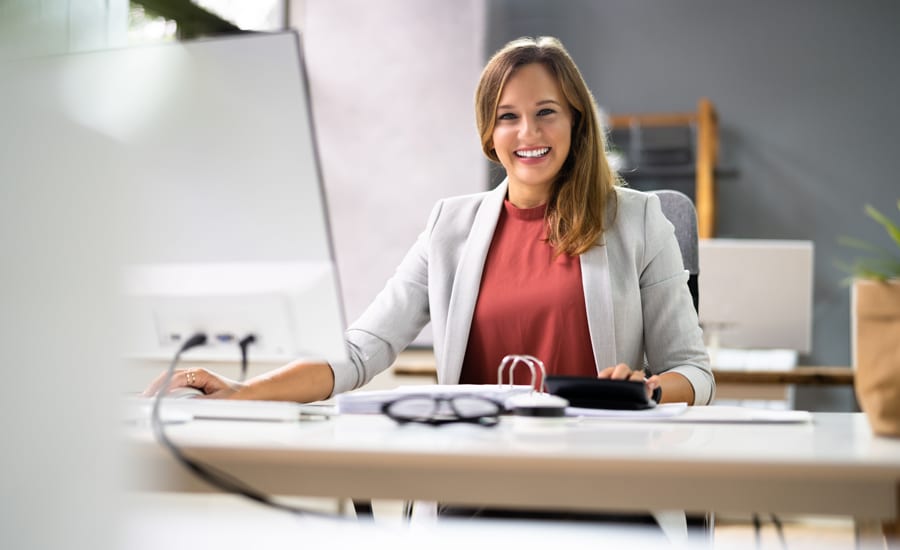 Ejecutiva del sector salud se encuentra sonriente frente a su escritorio